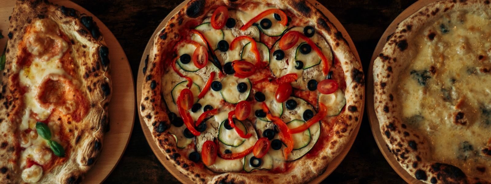 Kolme puu-uunipizzaa puupöydällä